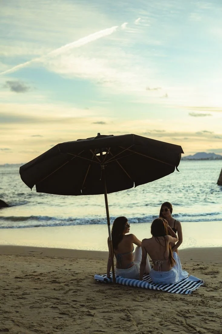 Casal sob um guarda-sol Rive diante do mar ao entardecer